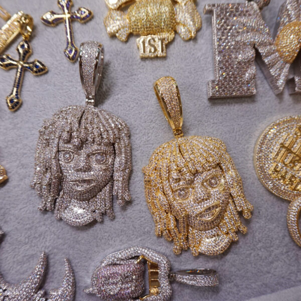 ICETOPLUXE collection display featuring gold and white iced out dreadlocks pendants alongside other hip hop jewelry