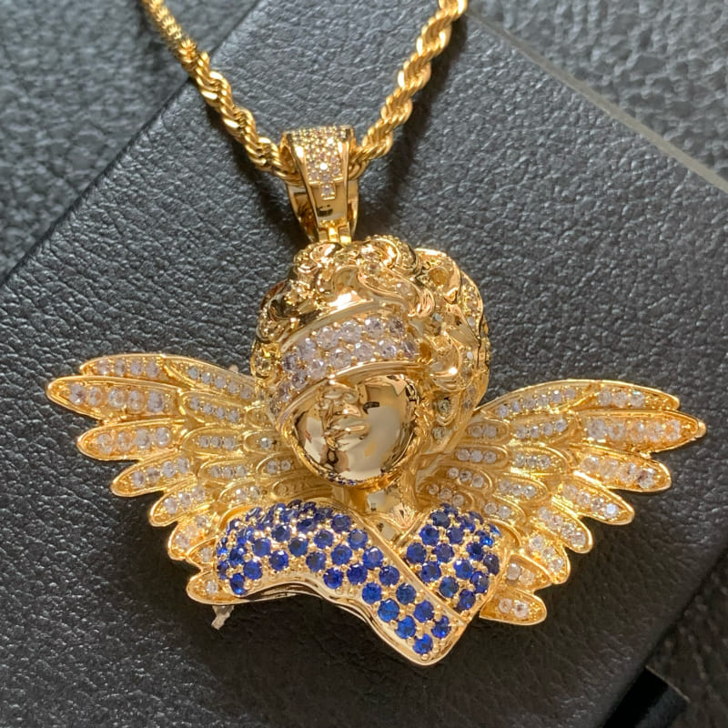 Front close-up of ICETOPLUXE 18K gold blindfold angel pendant with blue and white CZ stones, iced out hip hop jewelry for men