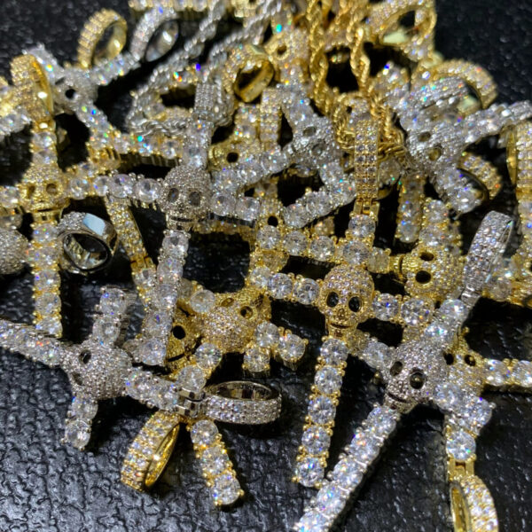 ICETOPLUXE assorted iced out skull cross pendants piled together, showcasing hip hop jewelry for men